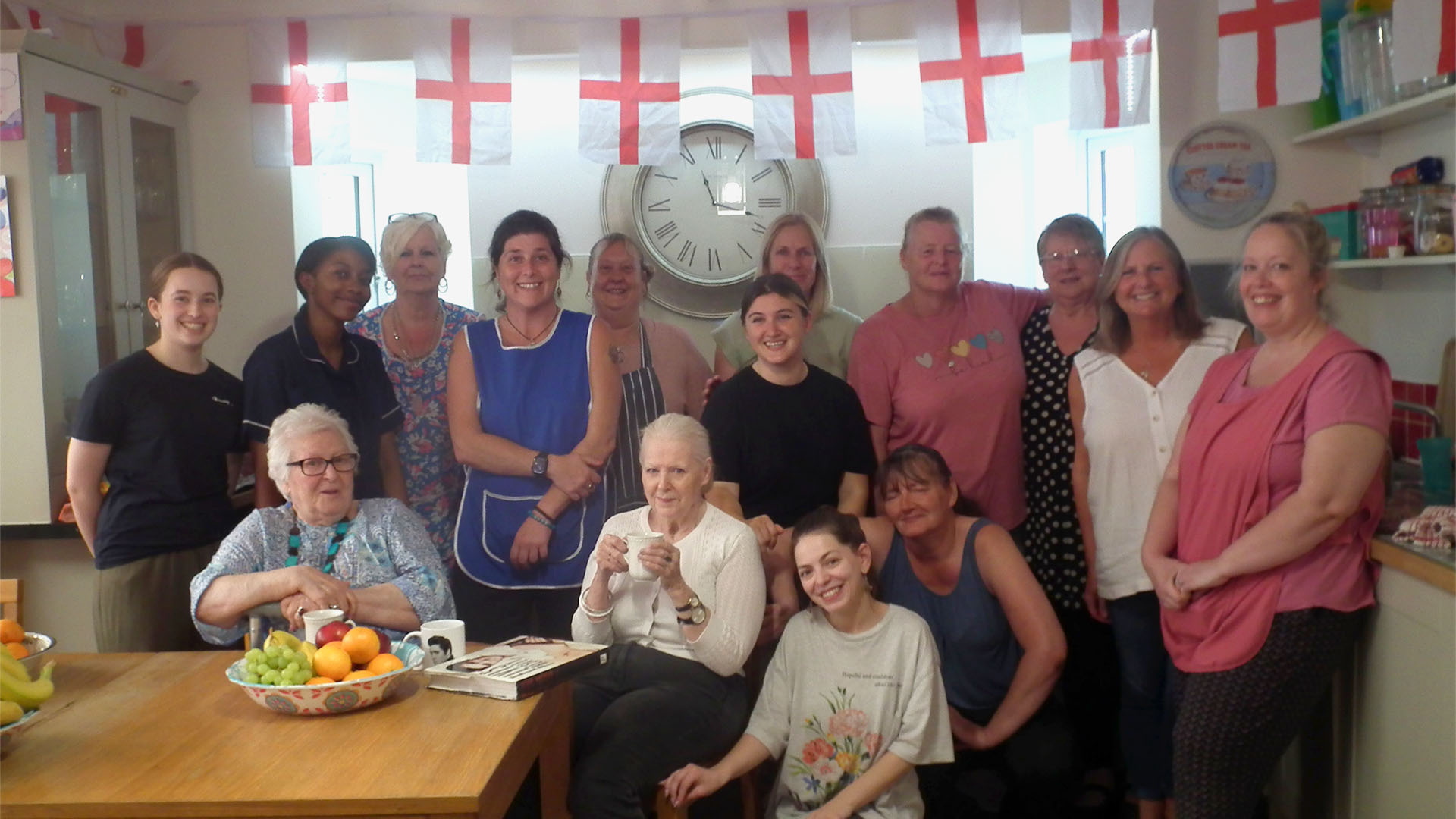 Group photo of some of the St Andrew's Care Home staff posing in the kitchen with two of the care home residents