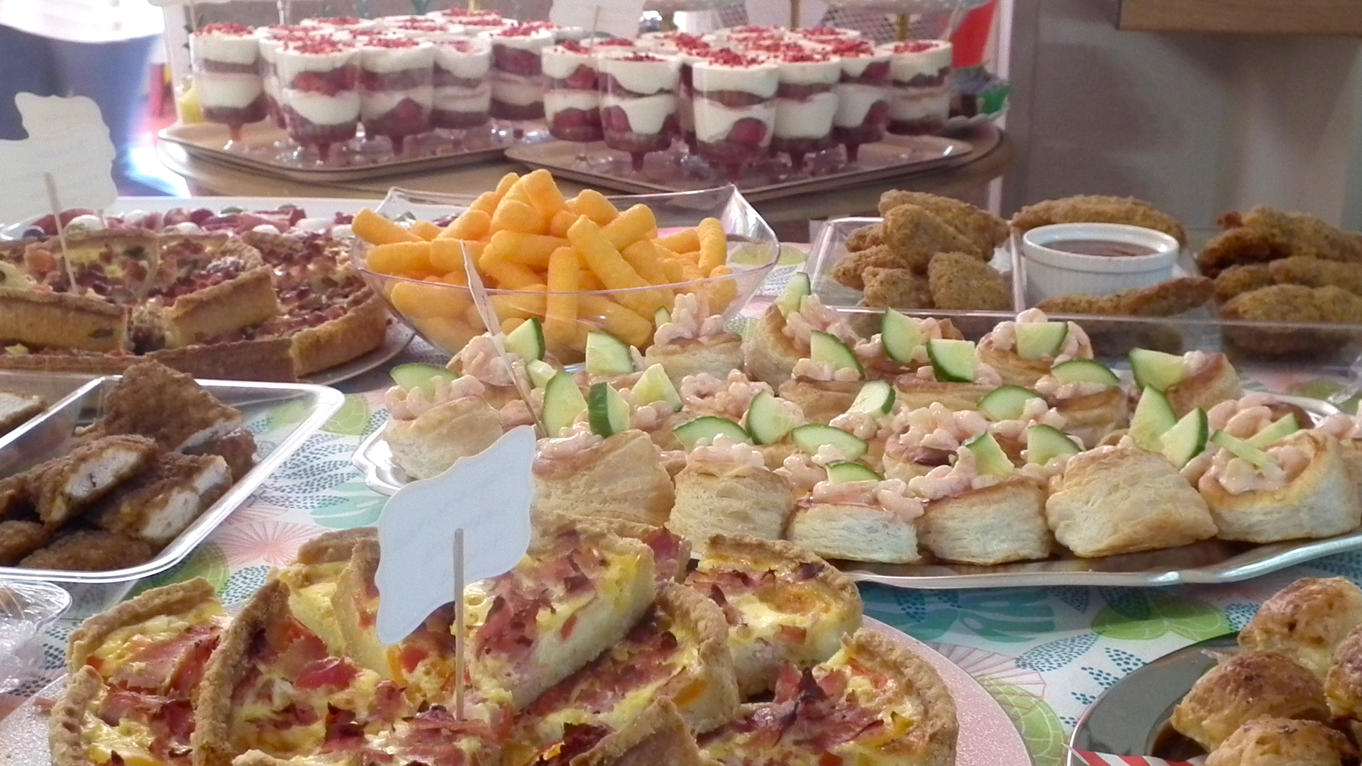 Tasty looking mini pizza slices, quiche, prawn and cucumber pastries, wotsits, dippers and sausage rolls look vibrant on the food table at the summer party