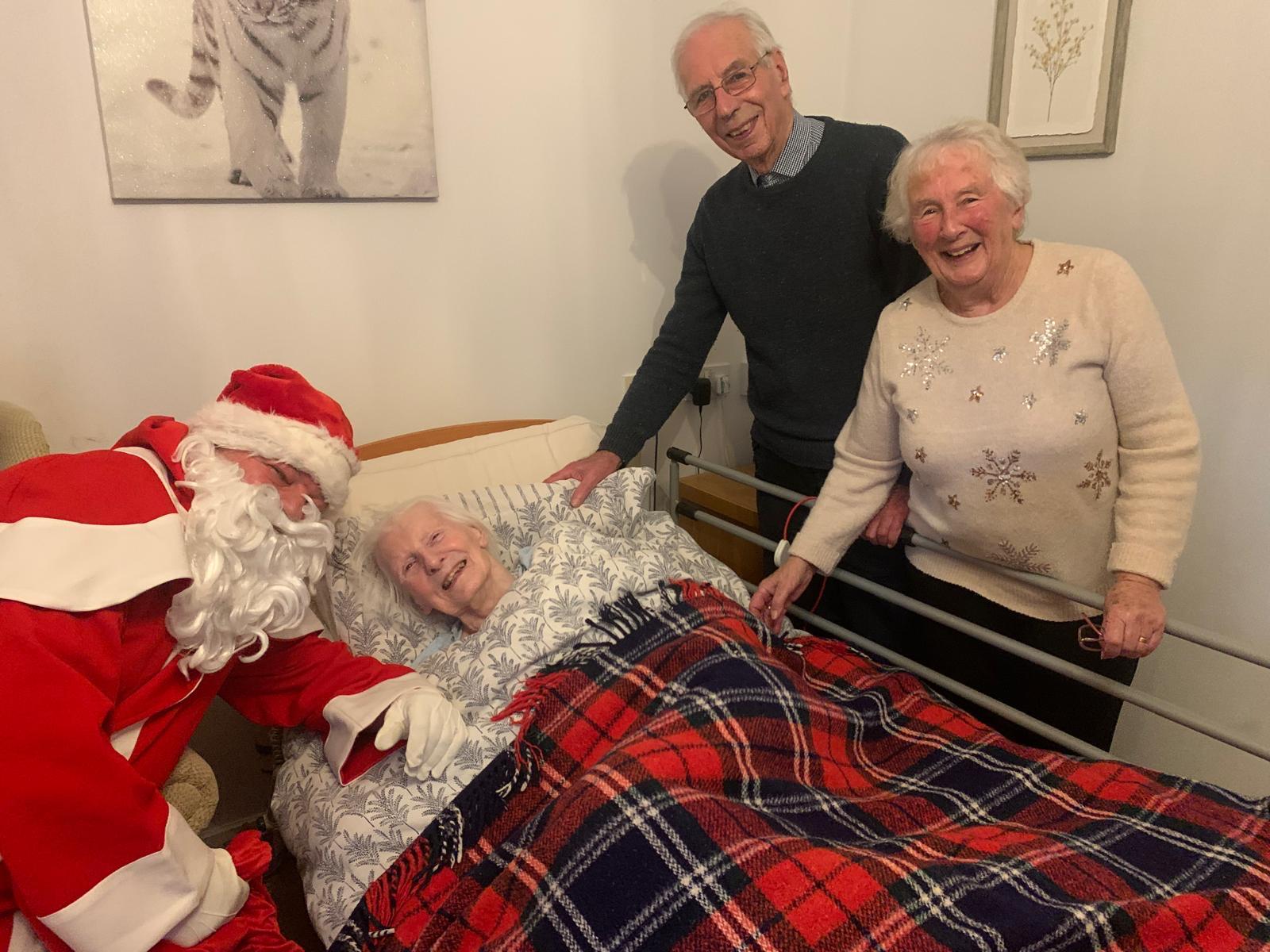 A resident and their relatives smile next to Father Christmas
