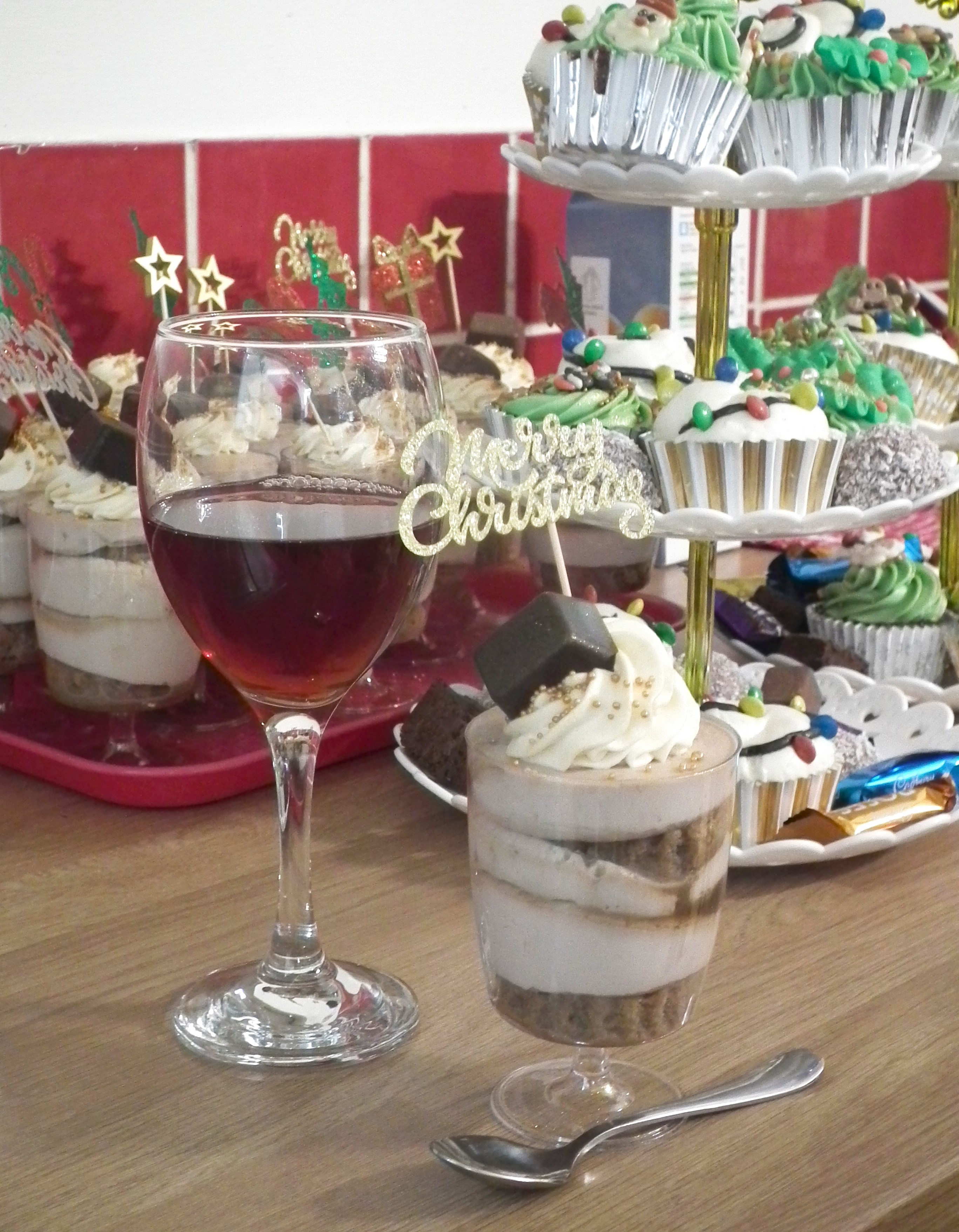 Close-up photo of the Baileys and chocolate tiramisu next to a glass of Glitterberry J2O. In the background you can see the decorated cupcakes and tiramisu cups