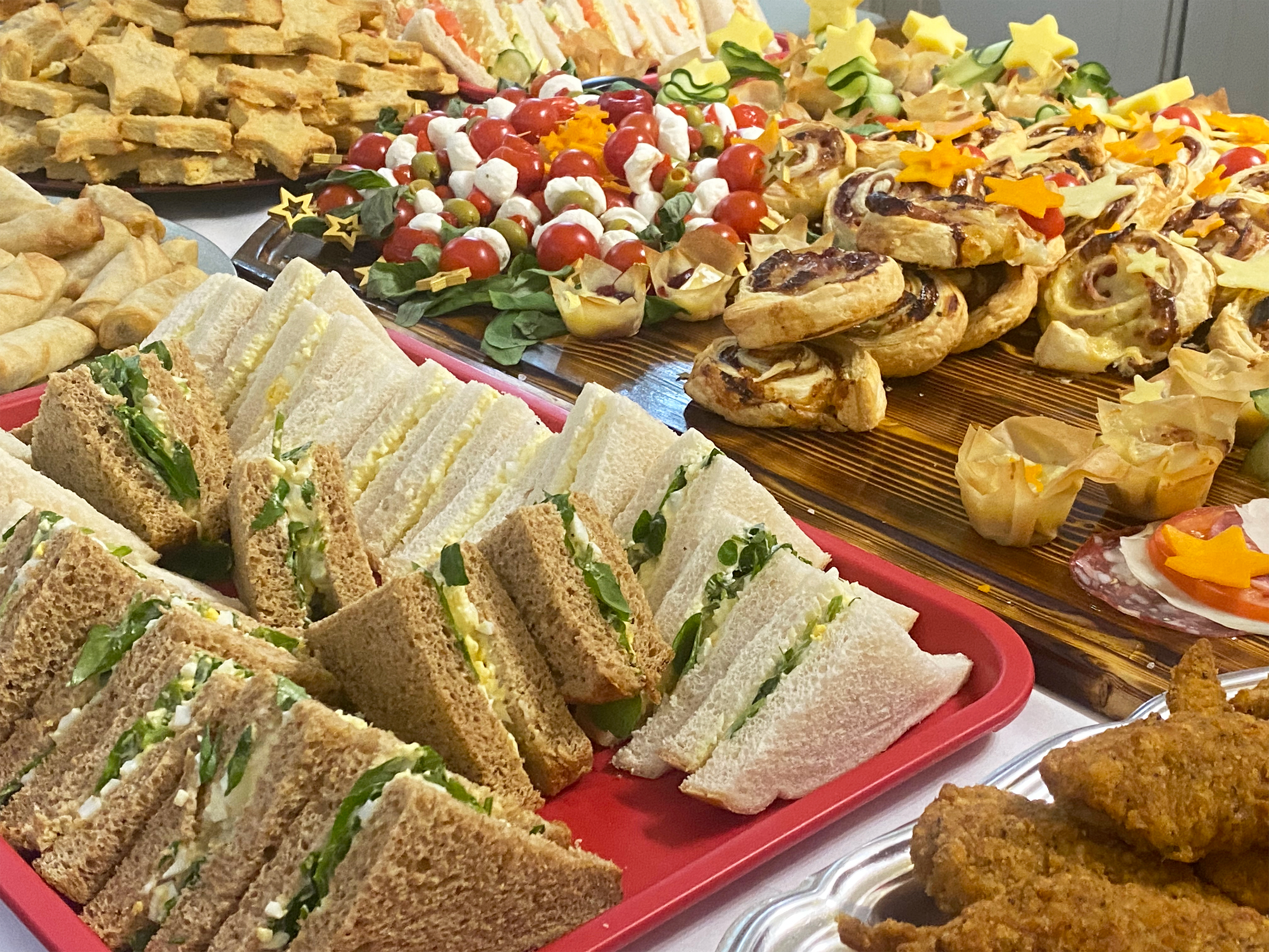 Close-up photo of the savoury buffet food, sandwiches, salad, spring rolls, swirl and other party food