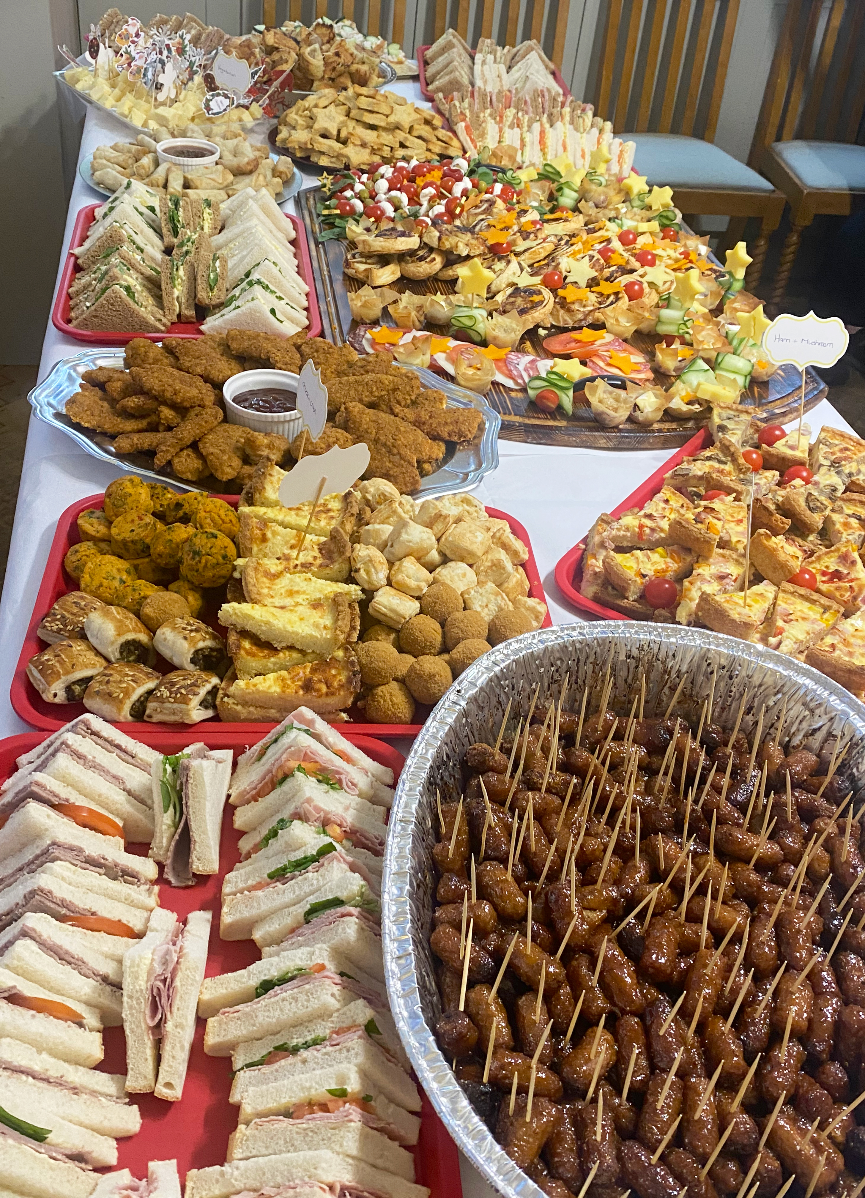 The variety of savoury foods at the buffet fill a whole table, including cocktail sausages, sandwiches, spring rolls, quiches and other festive party foods
