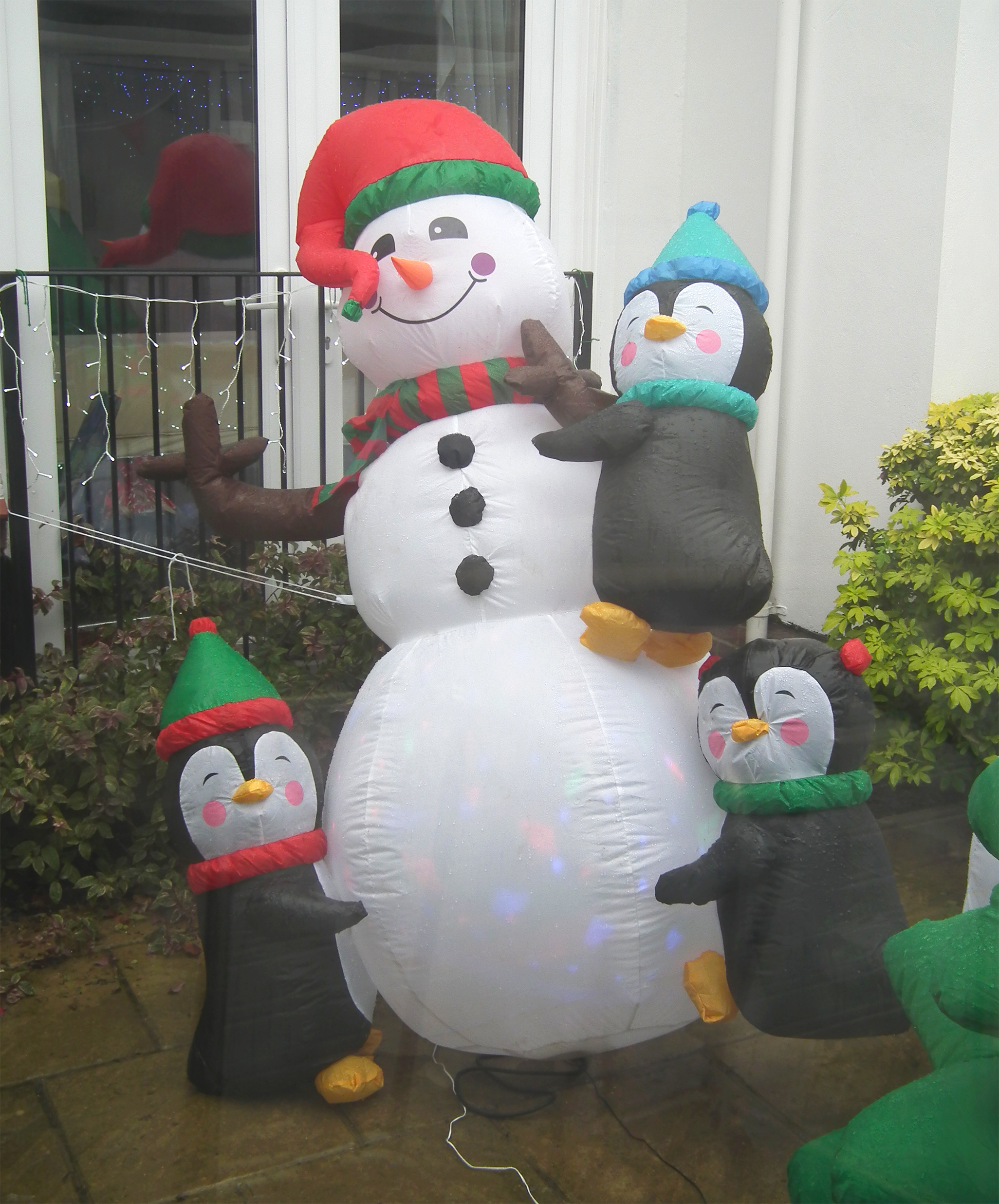Festive smiling snowman and penguins Christmas inflatables in the care home courtyard