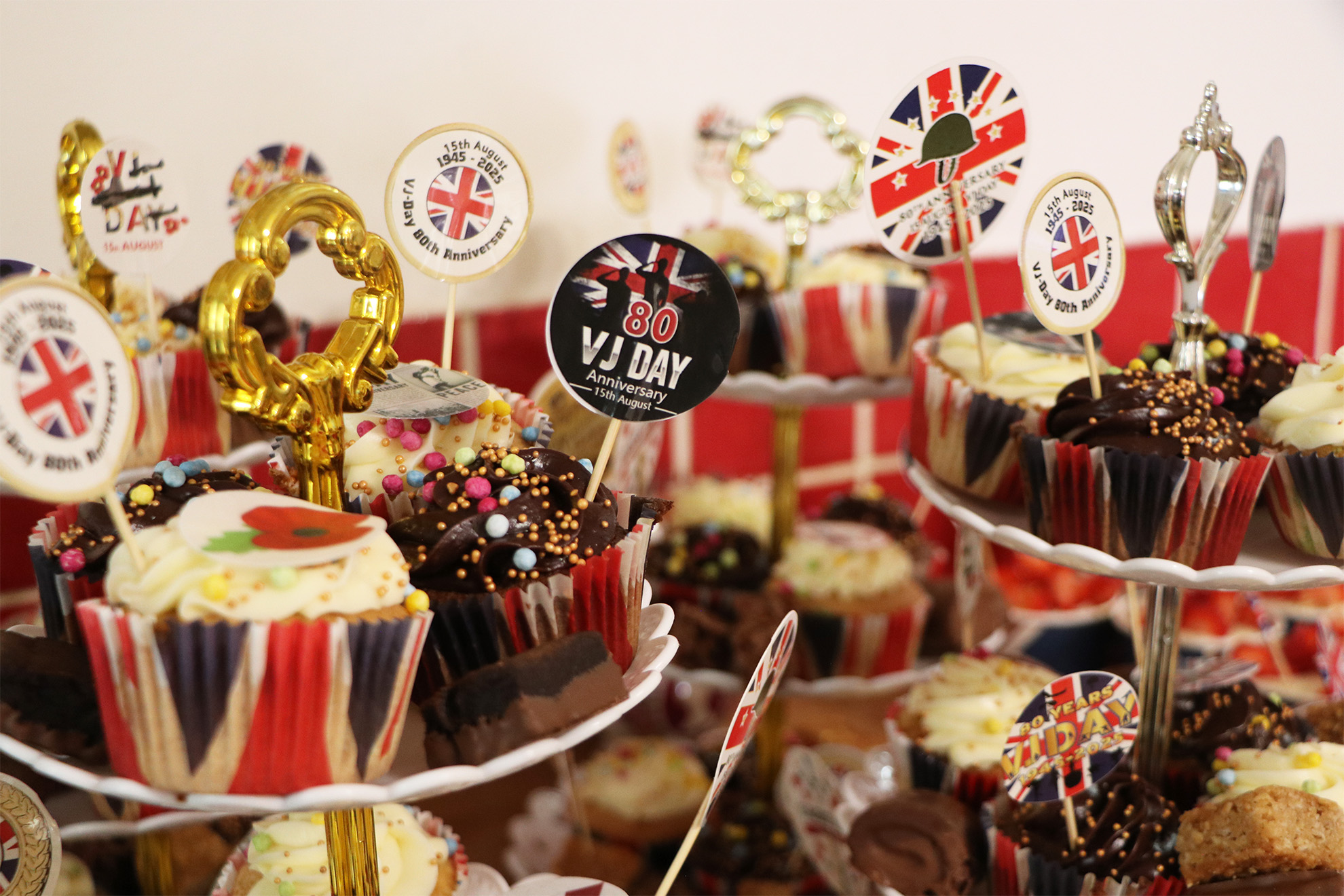 Close-up of chocolate and vanilla cupcakes and brownies decorated with sprinkles and VJ Day flags on tiered plate stands