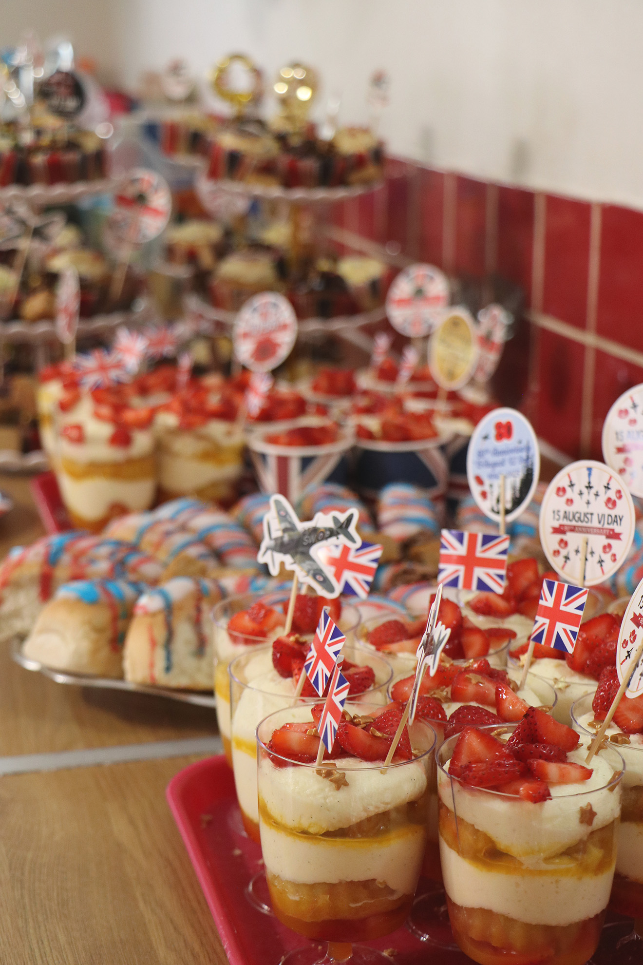A selection of beautifully presented desserts, including fruit and cream, iced buns and cakes decorated with sprinkles and British flags