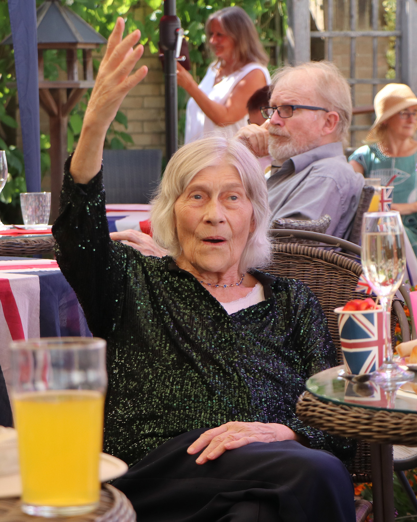 A resident wearing a sparkly dark green top holds her hand up and sings