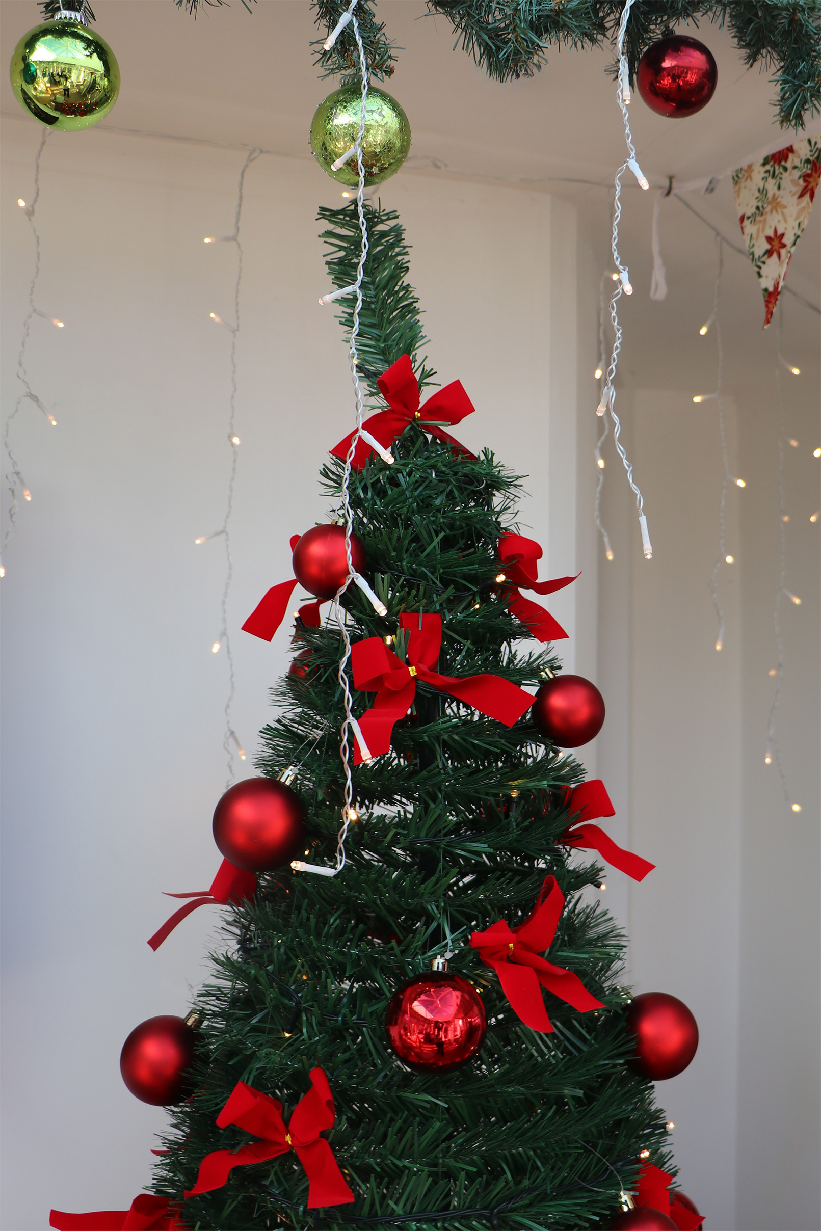 A Christmas tree covered in bright red bows and red baubles. The tree also has fairy lights around it.