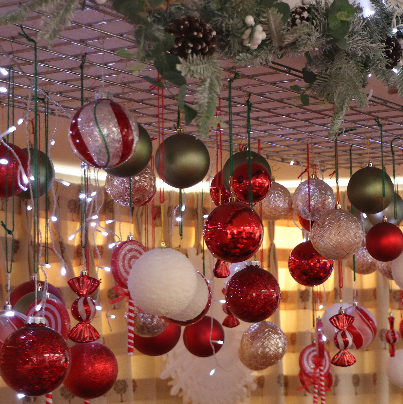 A closeup photo of the Christmas decorations including a winter garland and lots of red, silver and green baubles hanging down from the ceiling.